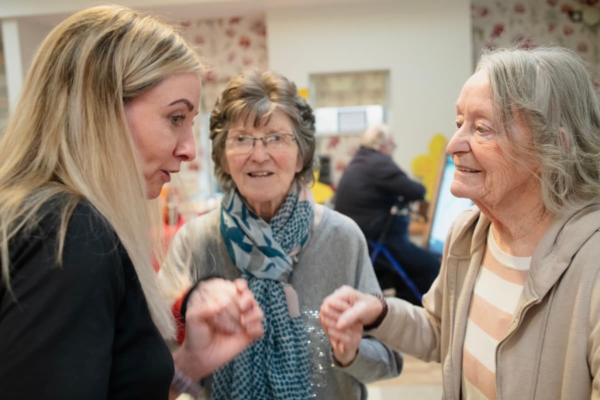 A caregiver in warm conversation with two residents